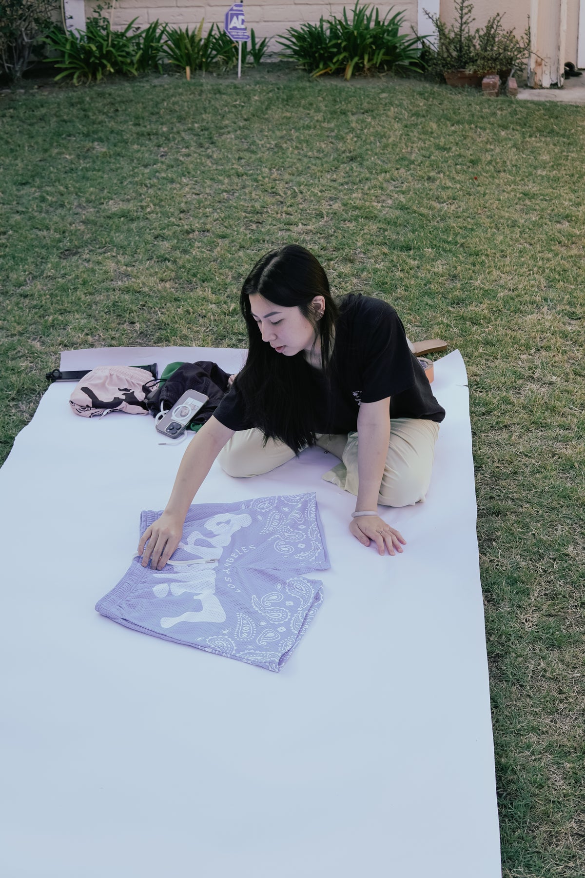 Person sitting on a blanket outdoors with a purple patterned fabric